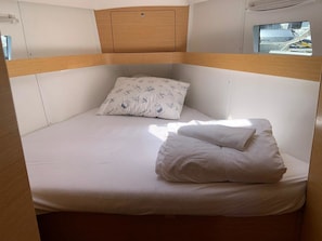 A bunk bed with a headboard, a pillow with a nautical pattern, and a window with a view of a dock. - Sun-Kissed Sailing Adventure in Split, Croatia (Split)