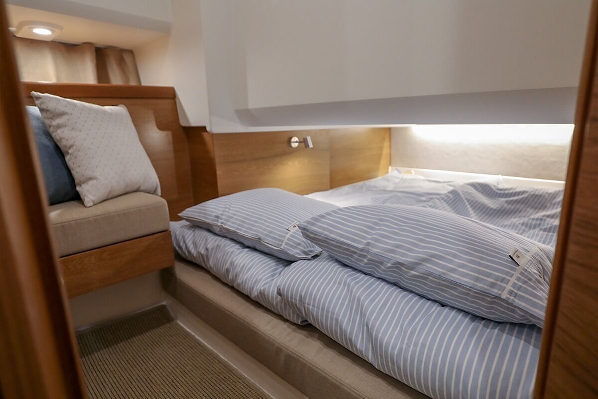 A compact bed with striped bedding and a wooden headboard.