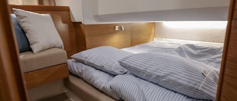 A compact bed with striped bedding and a wooden headboard.