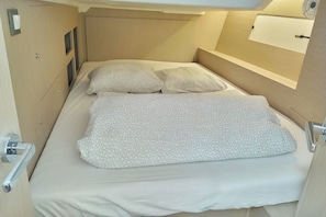 Ein schmales Bett mit einem gemusterten Überwurf, einem Kopfteil und einem Nachttisch mit Lampe.