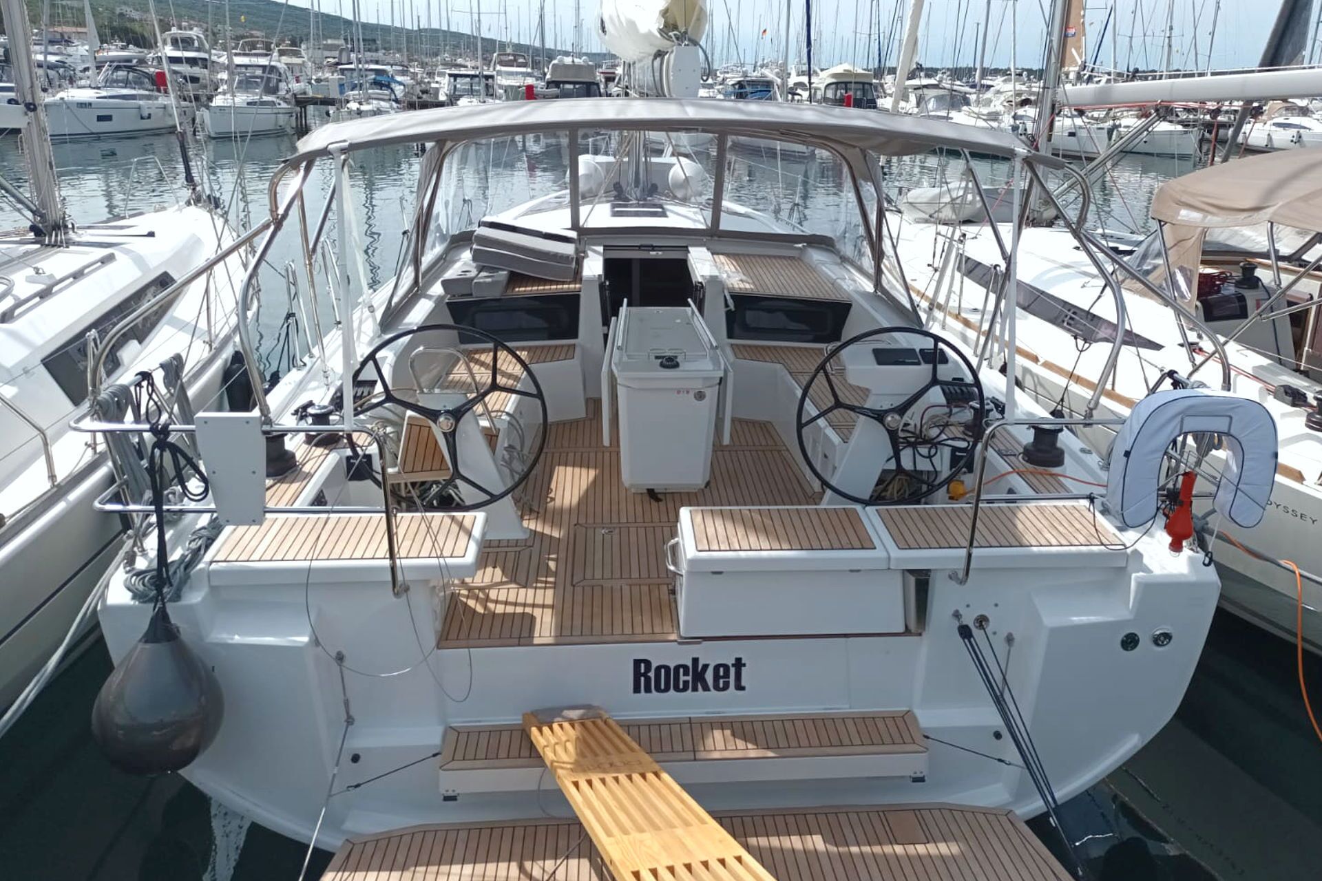 A yacht named 'Rocket' with a wooden deck, multiple steering wheels, and a lifebuoy.