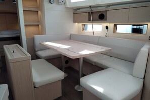 Ein kompaktes Wohnmobil-Interieur mit Esstisch, gepolsterten Sitzen und einer kleinen Küchenzeile.