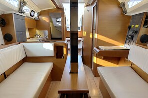 Un interior compacto con asientos, una mesa central, una kitchenette y un panel de control.