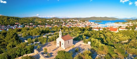 A small church surrounded by trees and a coastal town.