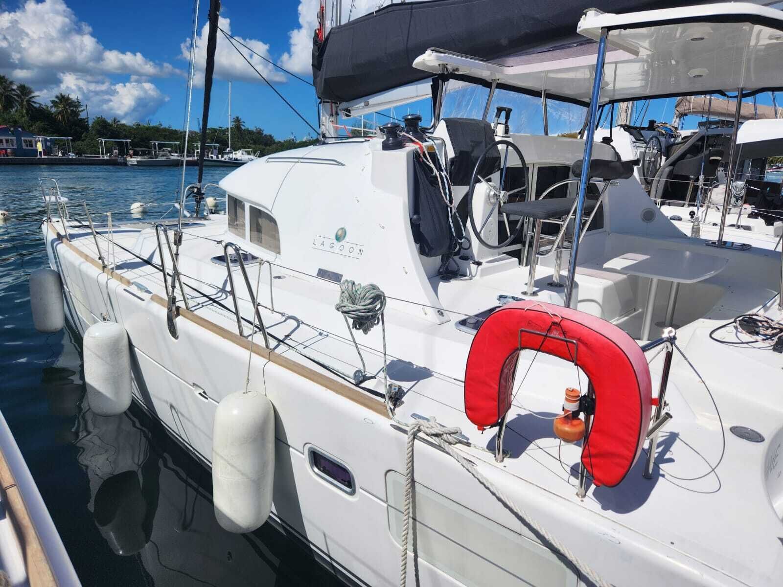 A white boat docked at a marina with a lifebuoy, a steering wheel, and a cabin with a window.