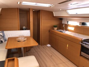 A compact kitchen with wooden cabinetry, a countertop, and a sink. - Sun-Kissed Sailing Adventure in Islas Sarónicas (Alimos)