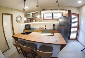 A kitchen with a central island, bar stools, a refrigerator, and a window with blinds. - Pier 106 (Tibau do Sul)