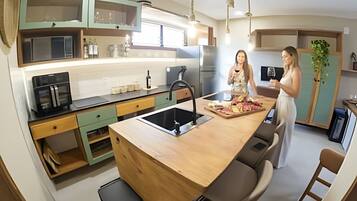 Cozinha moderna com ilha central, eletrodomésticos embutidos e área de refeições com banquetas.