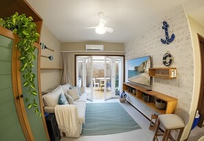 Ein Wohnzimmer mit einer Couch, einem Fernseher und Blick ins Freie.