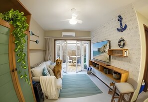A living room with a sofa, a dog, a TV, and a view of the outdoors. - Pier 106 (Tibau do Sul)