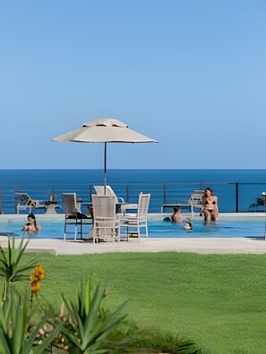 A pool area with lounge chairs, an umbrella, and a view of the ocean. - Pier 106 (Tibau do Sul)