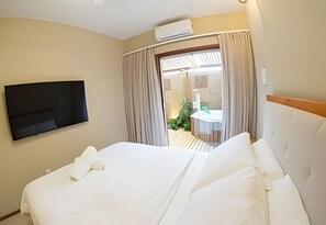 Habitación de hotel con cama, televisor, aire acondicionado, baño con ducha y vistas al exterior.