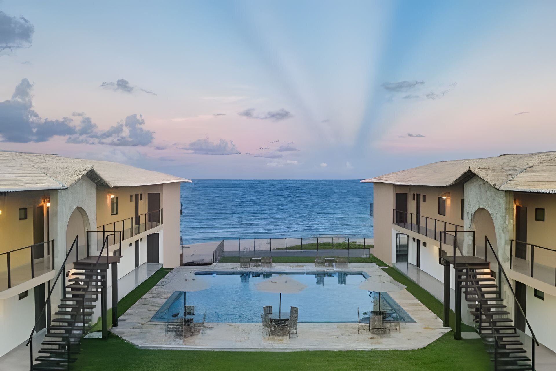 Un resort con piscina, edificios de dos pisos y vista al océano.