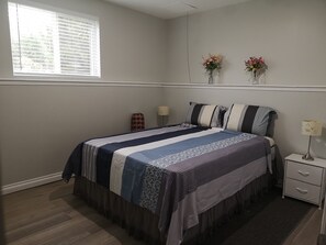 A bedroom with a bed, bedside tables, a window, and two wall-mounted flower vases. - Home listing (London)