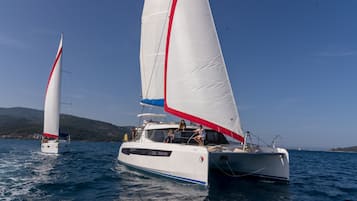 Zwei Segelboote auf ruhiger See unter blauem Himmel.