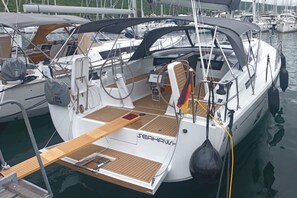 En segelbåt låg förtöjd vid en småbåtshamn, med ett trädäck, ett ratt och en livboj.