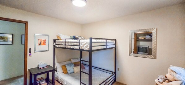 Habitación con literas, una mesita, un espejo y un peluche.