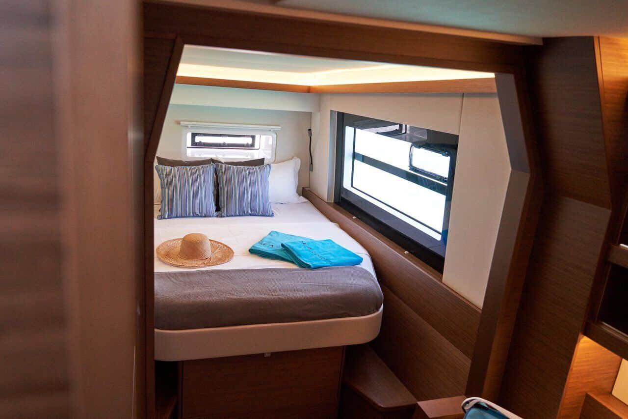 Un interior pequeño y bien iluminado con una cama, una ventana y una mesita.