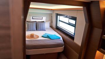 Un interior pequeño y bien iluminado con una cama, una ventana y una mesita.