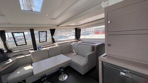 A modern interior with a dining area, seating, and a view of the marina. - Sun-kissed Sailing Adventure in Split-Dalmatia, Croatia (Seget Donji)