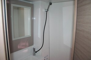 Een badkamer met een douche, een spiegel en een wastafel.