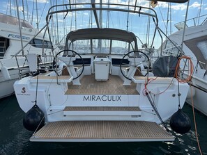 A white yacht named MIRACULIX docked at a marina with multiple boats around.