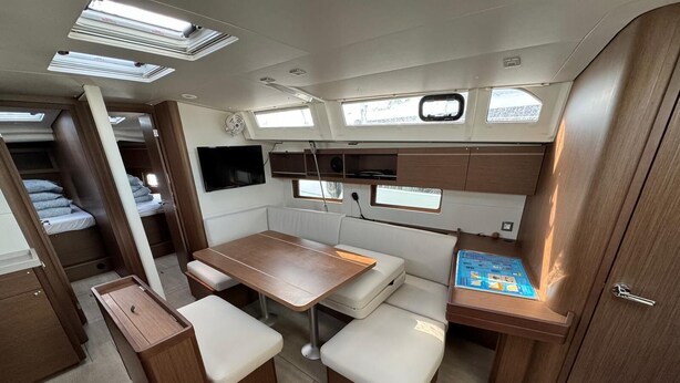 Een compact interieur van een camper met een eethoek, zitplaatsen en een klein tafeltje met een handleiding.