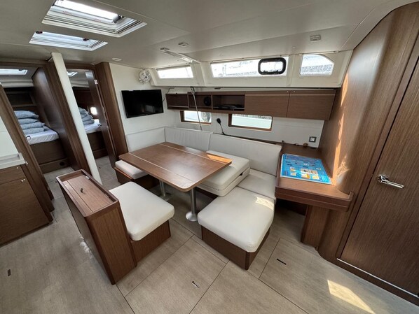 A compact RV interior with a dining area, seating, and a small table with a manual.