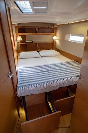 Een compacte, goed verlichte slaapkamer met een bed, nachtlampjes en een dakvenster.