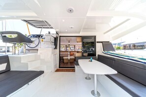 A modern interior with a dining area, seating, and a view through the glass. - Sun-Kissed Sailing Adventure in Islas Esporadas (Skiathos)