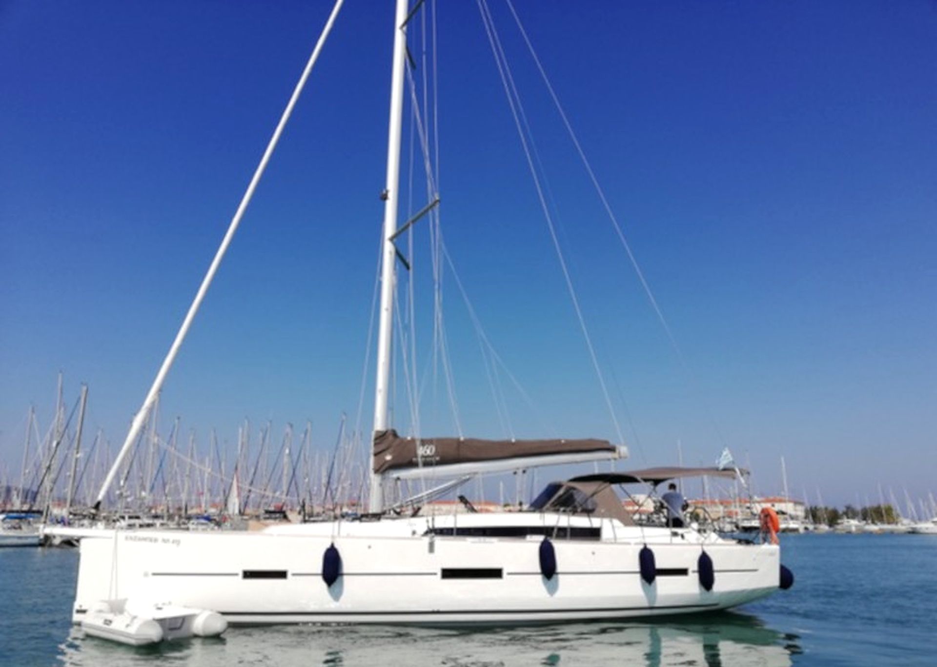 A sailboat docked at a marina with multiple other boats in the background.