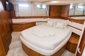 A bedroom with a large bed, wooden headboard, a small bedside table, and a TV mounted on the wall.