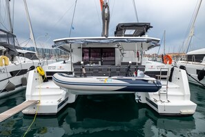 Ein Hafen mit einem weißen und blauen Boot, das vertäut ist, mit überdachter Sitzgelegenheit, einer kleinen Kabine und einem Rettungsring.