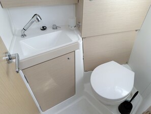 Un baño con lavamanos blanco, inodoro y zona de ducha.