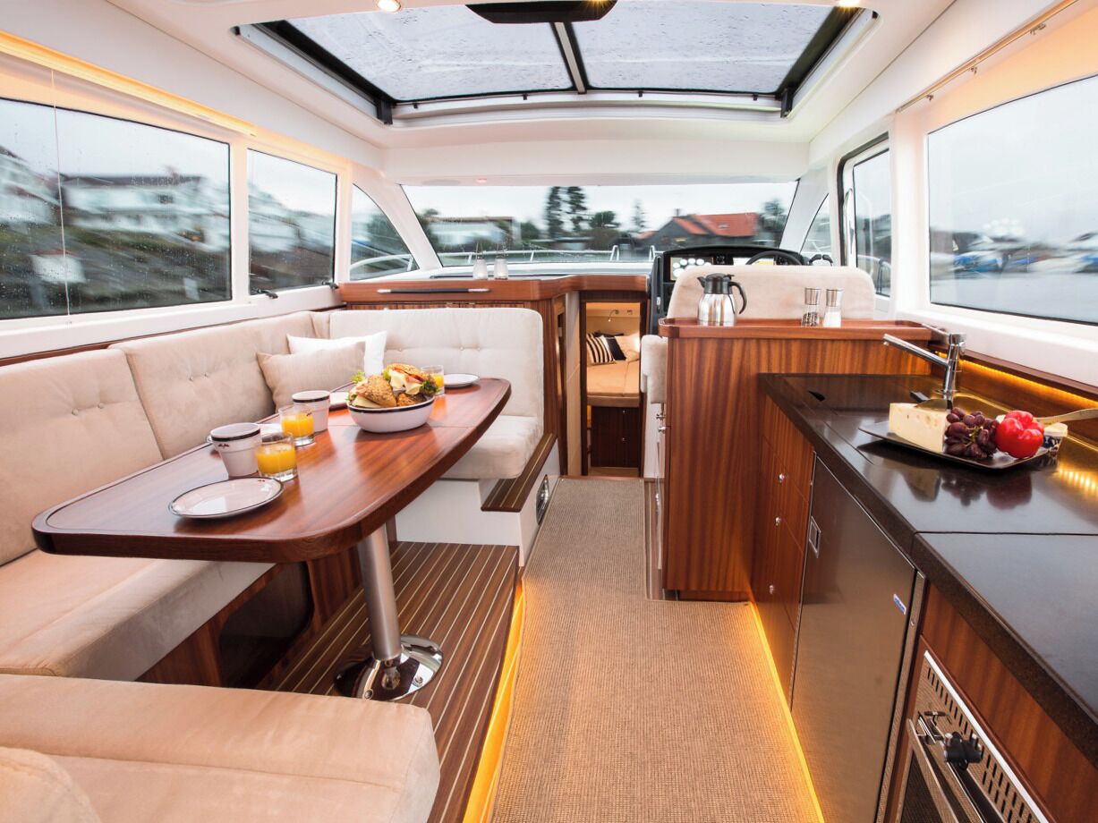 Interior de un yate con comedor, cocina y zona de estar.