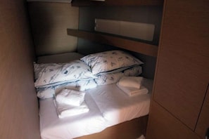 A small, compact bed with a headboard, a pillow with a nautical pattern, and a neatly folded towel on the side. - Sun-kissed Sailing Adventure in Split-Dalmatia, Croatia (Seget Donji)