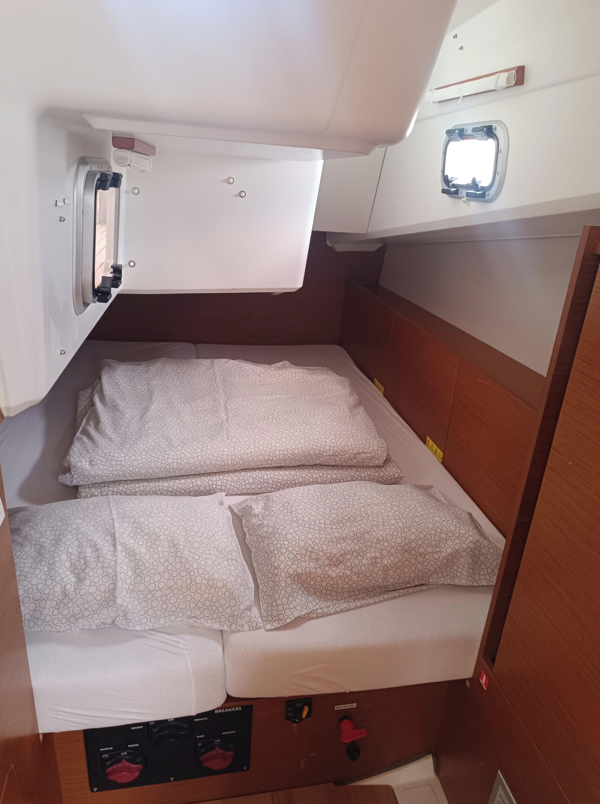 Een compacte hut met een stapelbed, een bedieningspaneel met stroomonderbrekers en een klein raam.