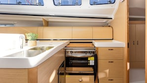 A compact galley with a sink, stove, and storage drawers. - Sun-Kissed Sailing Adventure in Northern Croatia (Punat)