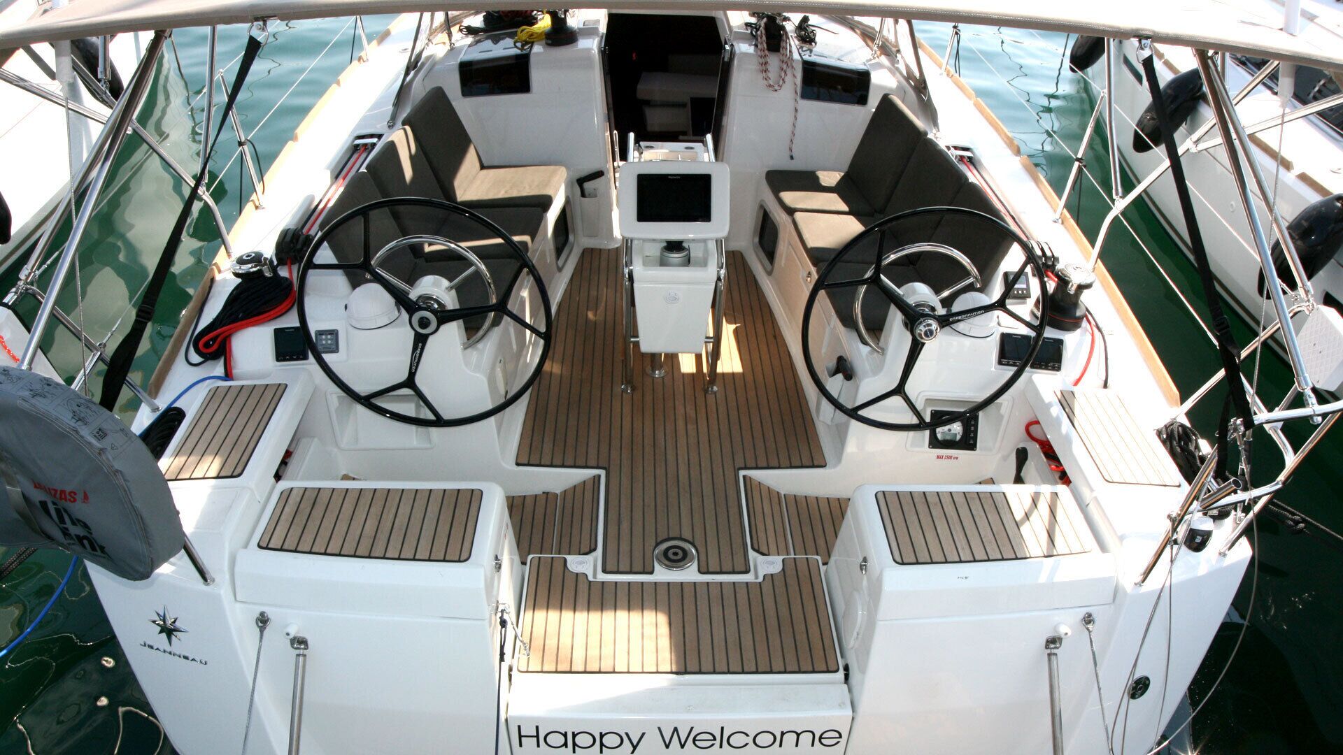 Cubierta de barco con dos timones, una consola central y un cartel que dice 'Happy Welcome'.