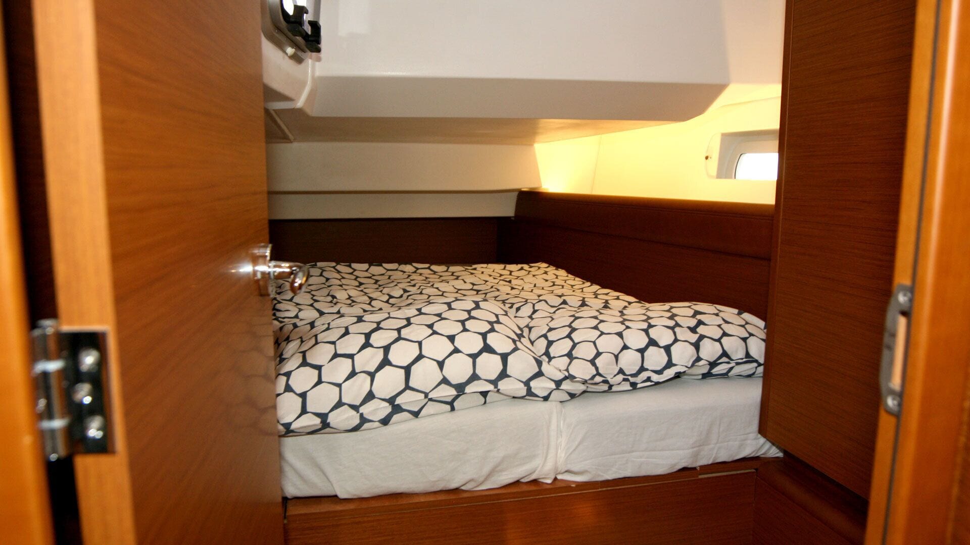 Ein kleiner, abgeschlossener Schlafbereich mit Bett, Kopfteil und Tür.