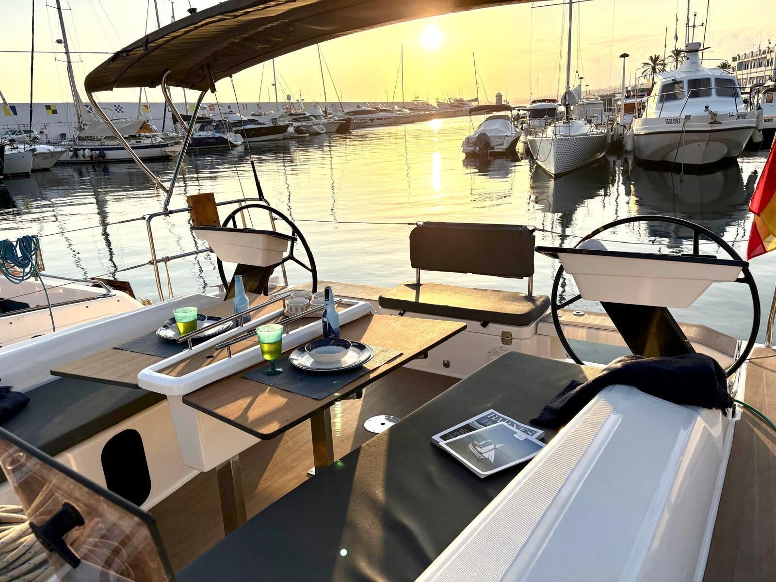 A marina with boats docked, a table with a bench, and a view of the sunset.