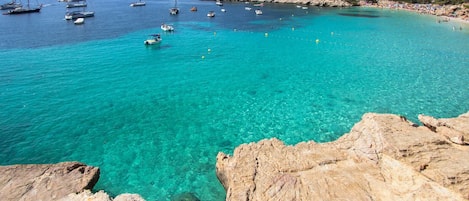 Een kustgebied met helder turquoise water, rotsachtige oevers en boten.