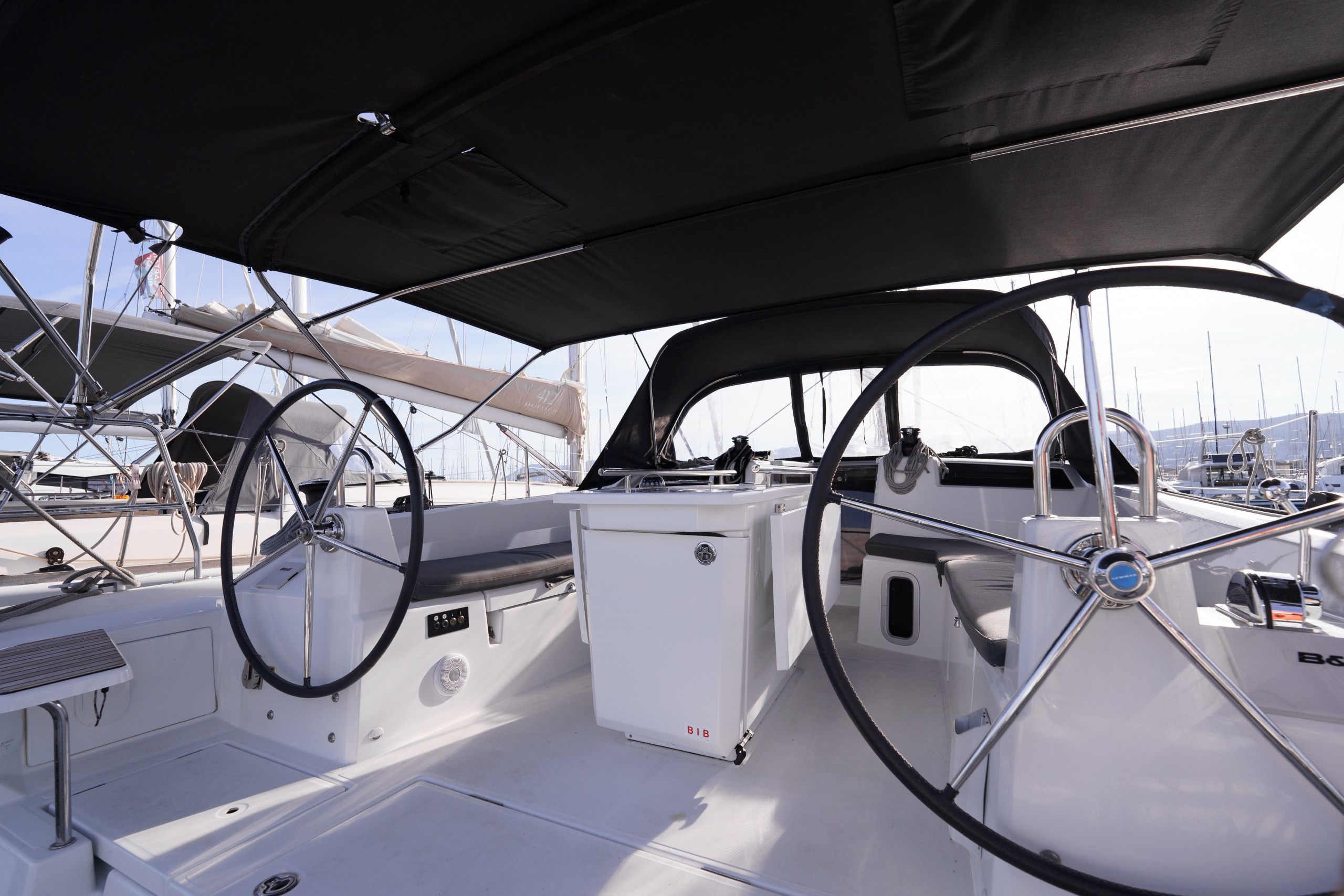 Cubierta de un velero con timón, panel de control y una pequeña mesa.