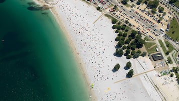 Luchtbeeld van een strand met een parkeerplaats en gebouwen.