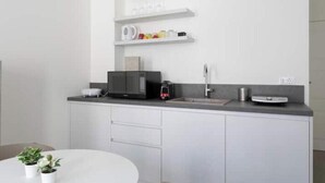 Une cuisine moderne avec des meubles blancs, un four à micro-ondes, une machine à café et un petit espace de comptoir.