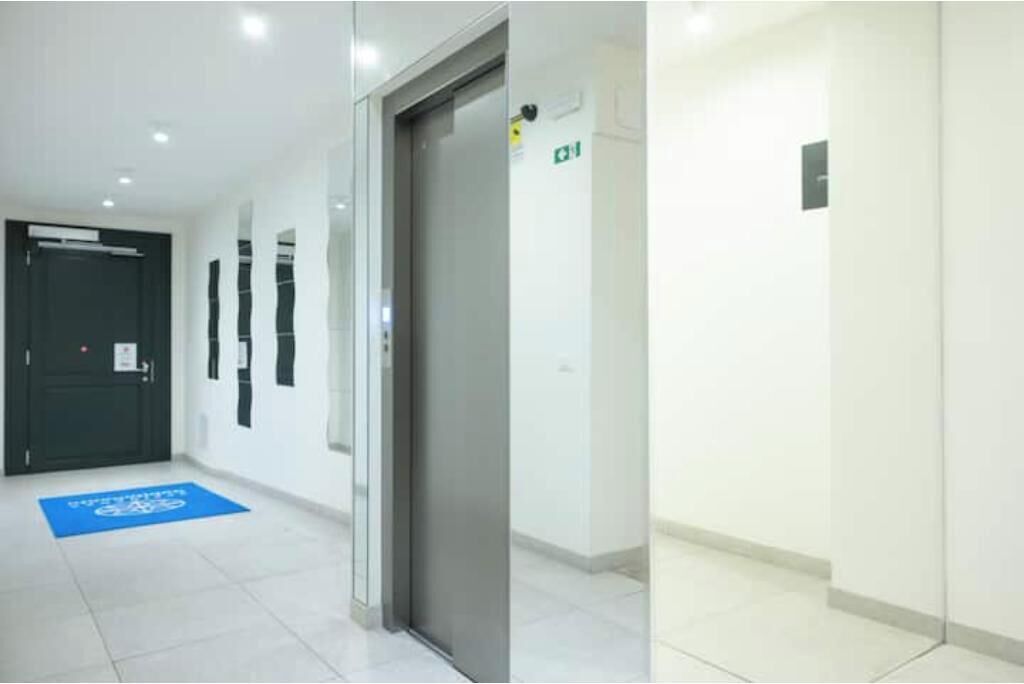 Un couloir avec une porte, un tapis bleu et un panneau indiquant la sortie.