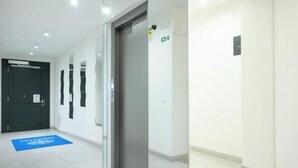 Un couloir avec une porte, un tapis bleu et un panneau indiquant la sortie.