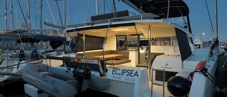 A marina with a boat named 'ECLIPSEA' docked, featuring a covered deck area, a control station, and a visible lifebuoy.