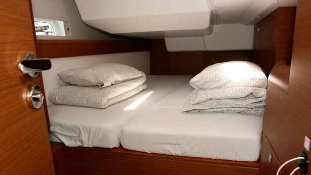 Una cabaña compacta con literas, una pequeña zona de descanso superior y una puerta de madera.
