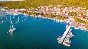 Vista aérea de un pueblo costero con un puerto deportivo, barcos y casas.